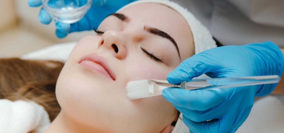 Beauty salon, cosmetician aplying facial peeling mask. Skin treatment concept.